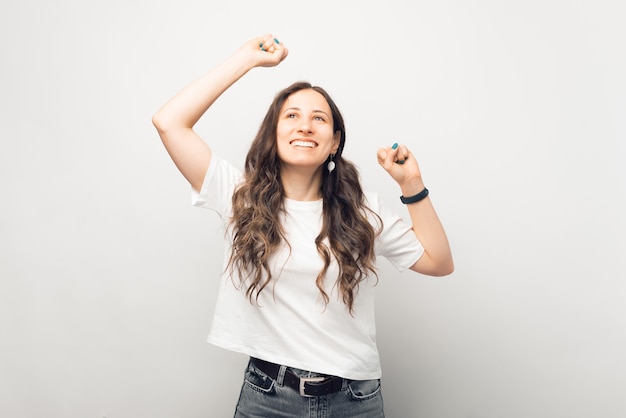 Opgewonden jonge vrouw maakt het winnaarsgebaar terwijl ze omhoog kijkt.