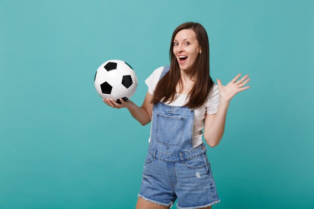 Opgewonden jonge vrouw voetbalfan opvrolijken ondersteuning favoriete team met voetbal geïsoleerd op blauwe turquoise muur achtergrond. Mensen emoties sport familie leisure lifestyle concept. Bespotten kopie ruimte.