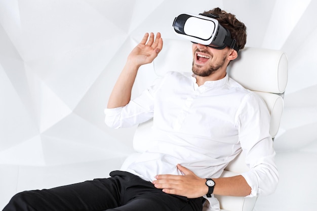 Opgewonden jongeman doet ervaring op met het gebruik van een vrheadset-bril van virtual reality die gebaren maakt met...