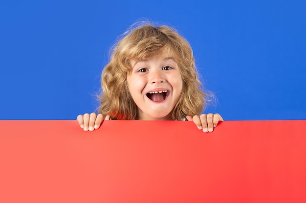 Opgewonden jongen jongen op studio geïsoleerde achtergrond kind houdt rode lege banner op studio achtergrond advertentie