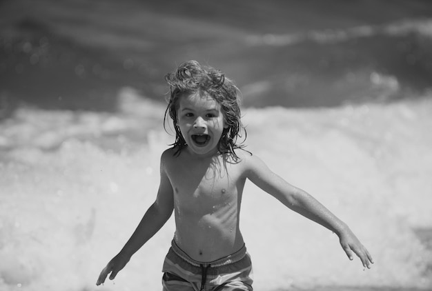 Opgewonden jongetje spelen op het strand aan zee