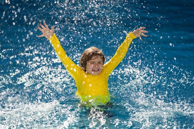 Opgewonden kind zwemt een klein kind dat speelt in het blauwe water van het zwembad op een tropisch resort aan de