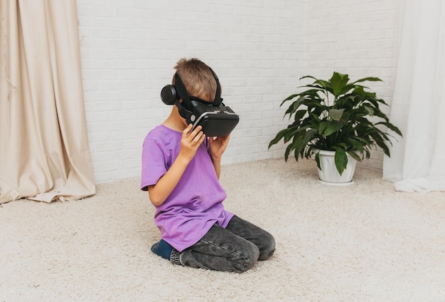 Opgewonden klein jongenskind in virtual reality-bril zit thuis op de vloer.