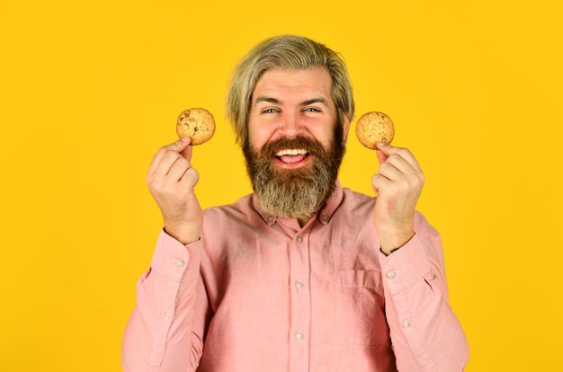Opgewonden man met cookies. bebaarde hipster houden koekje. vol calorieën. concept van schadelijk voedsel. gebak en dessert. bakkerij winkel advertentie. man op dieet. Man met een koekje in zijn hand.