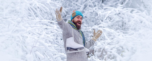 Opgewonden man met schaatsen in de winterdag jonge man in de winter buiten man portret voor banner grappig