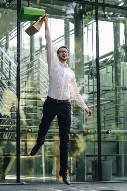 Opgewonden man springen met papieren zakken