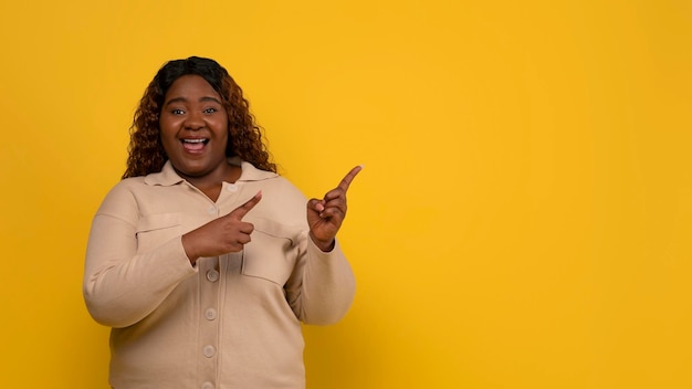 Opgewonden mollige Afrikaans-Amerikaanse dame wijst naar vrije ruimte.