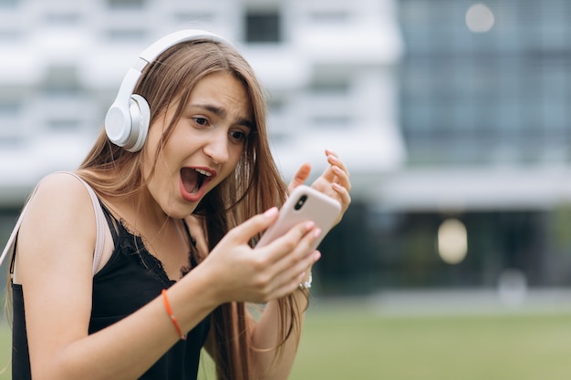 Opgewonden mooi meisje winnen en verrast op zoek naar haar smartphone