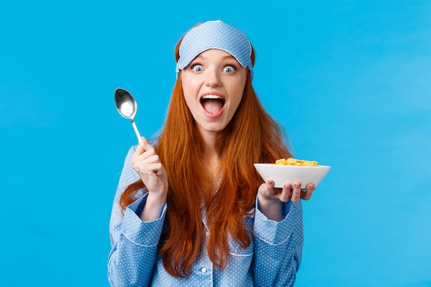 Foto opgewonden, overweldigd gelukkig roodharige blanke vrouw het eten van ontbijtgranen