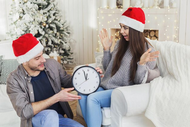 Opgewonden paar met wekker met vijf minuten voor middernacht, geschokt van bijna nieuwjaar, kopieer ruimte