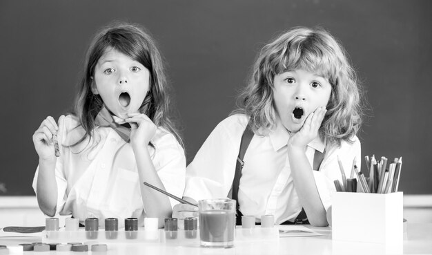 Opgewonden school verraste kinderen die kleurrijke foto's tekenen met potloodkrijtjes in klass...