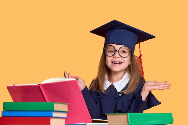 Opgewonden schoolmeisje in afstuderen outfit studeren met schoolboeken