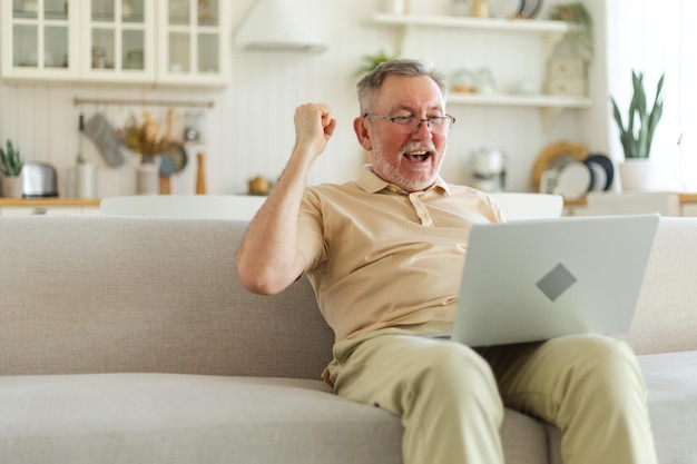 Opgewonden senior man van middelbare leeftijd euforische winnaar oudere volwassen grootvader die laptop leest gr