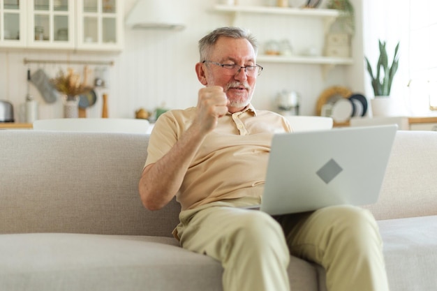 Opgewonden senior man van middelbare leeftijd euforische winnaar oudere volwassen grootvader die laptop leest gr