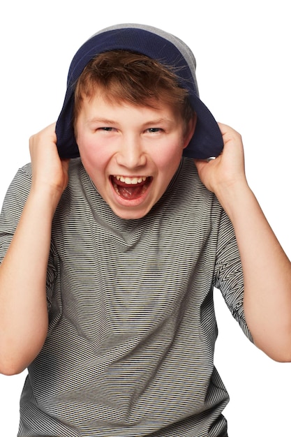 Foto opgewonden tot het uiterste een tiener die zijn muts over zijn oren trekt terwijl hij schreeuwt