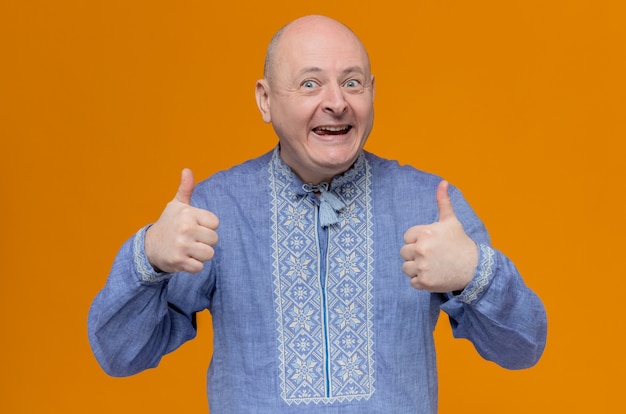 Opgewonden volwassen Slavische man in blauw shirt duimen omhoog