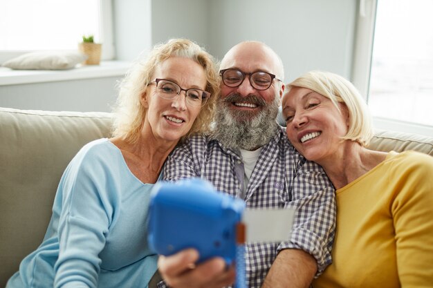 Opgewonden volwassen vrienden nemen selfie op instant camera