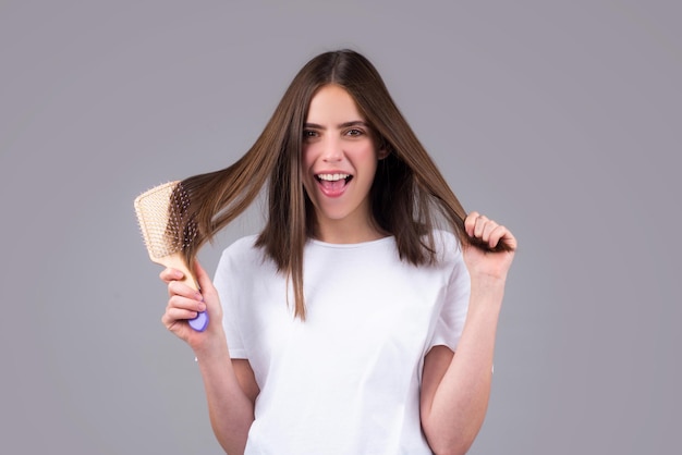 Opgewonden vrouw kamt haar gezond haar en kamt gezond lang steil vrouwelijk haar van dichtbij