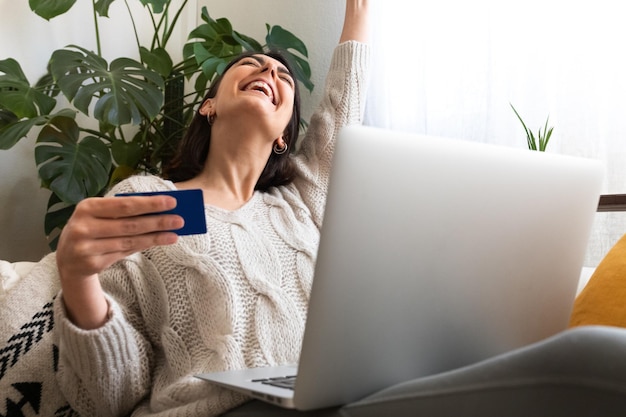 Foto opgewonden vrouw met armen omhoog online winkelen thuis met behulp van laptop en creditcard kopieer ruimte