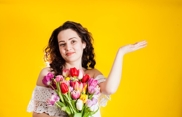 Opgewonden vrouw met kleurrijke tulpen over levendige gele muur binnen