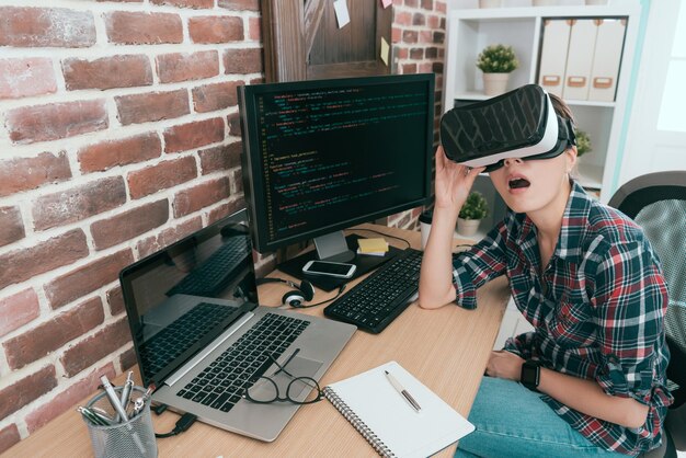 opgewonden vrouwelijke datasysteemontwikkelaar voor schoonheid die een virtual reality-bril gebruikt die 3D-simulatorvideo op kantoor ervaart en zich geweldig voelt.