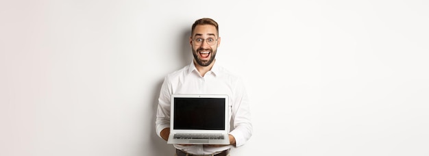 Opgewonden zakenman die iets op het scherm van de laptop laat zien dat gelukkig staat op een witte achtergrond