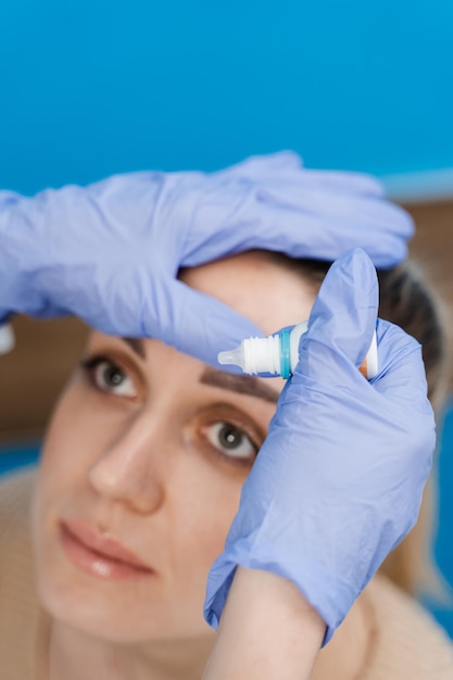 안과의사가 안구건조증 치료를 위해 여성 환자의 눈에 안약을 떨어뜨린다.