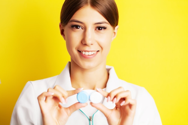 The ophthalmologist holds a container with contact lenses near the eyes