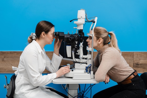 Ophthalmologist with slit lamp examines eyes and cornea of woman Ophthalmologist illuminates eye of patient with light from slit lamp to diagnose the eyes and cornea