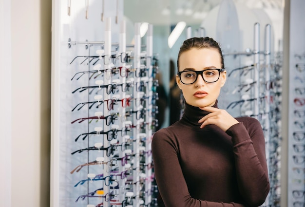 Ophthalmology Young woman is choosing a glasses in optician store Eyesight correction