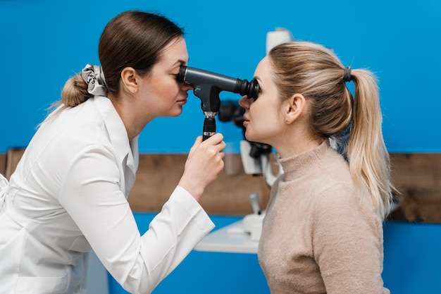 Ophthalmoscopy ophthalmologist examines the eyes of woman with ophthalmoscope ophthalmology consultation with an optometrist in a medical clinic