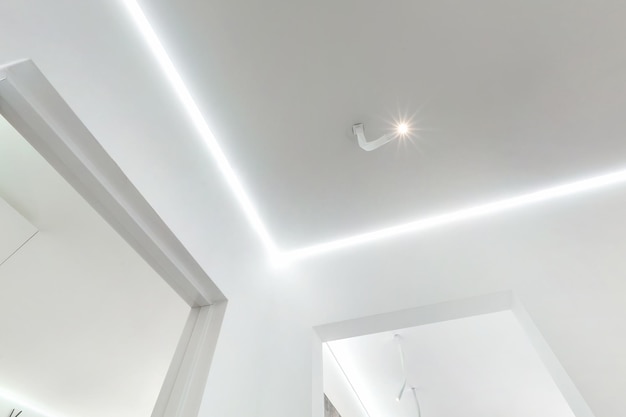 Opkijkend op verlaagd plafond met halogeenspots lampen en gipsplaatconstructie in lege ruimte in appartement of huis Spanplafond wit en complexe vorm