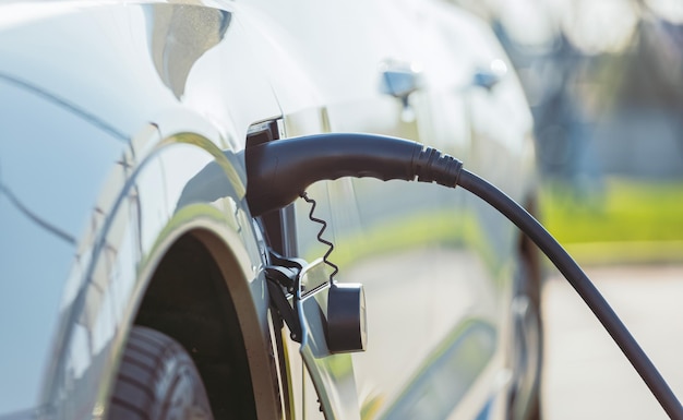 Opladen van een elektrische auto met een aangesloten stroomkabel close-up Het concept van ecologisch vervoer