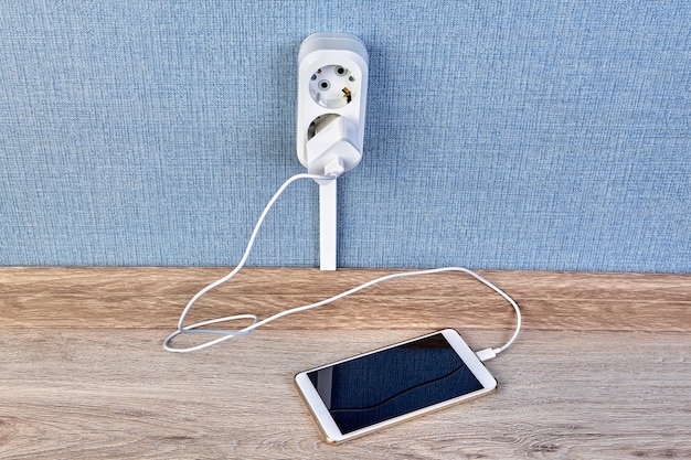 Opladen van smartphone met oplader en kabel, aangesloten op stopcontact.