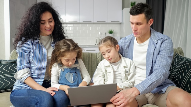 Oplettende ouders kijken naar opgewonden broers en zussen die op de laptop spelen