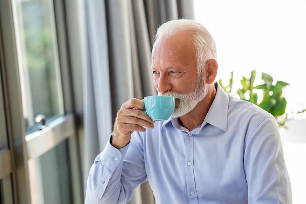 Opname van een senior financieel zakenman die in zijn kantoor zit en een kop koffie drinkt terwijl hij een pauze neemt