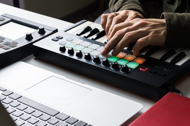 Foto opnemen van elektronische muziek track met draagbare midi keyboard op laptopcomputer in home studio