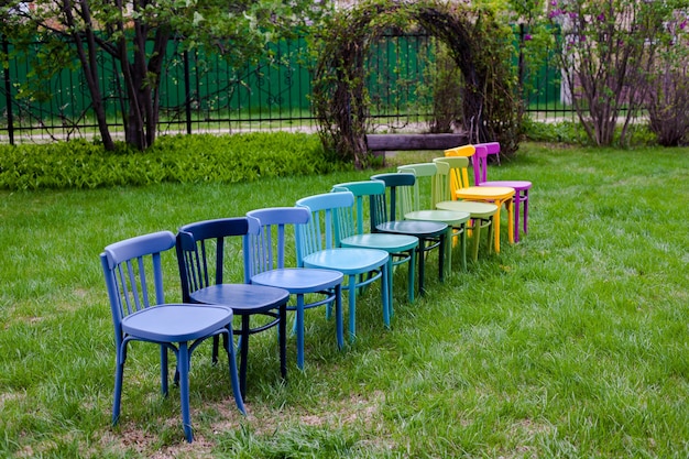 Opnieuw geverfde gerenoveerde houten Weense stoelen kleurrijke stoelen staan op het grasveld als symbool van geweten...