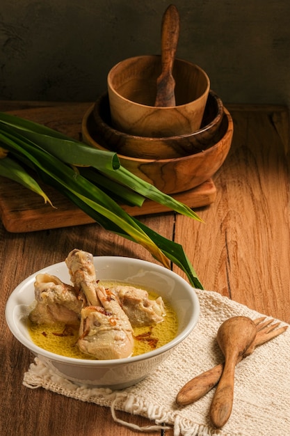 Opor Ayam is served on a wooden table. Opor is a traditional Indonesian food made from chicken cooked with coconut milk sauce