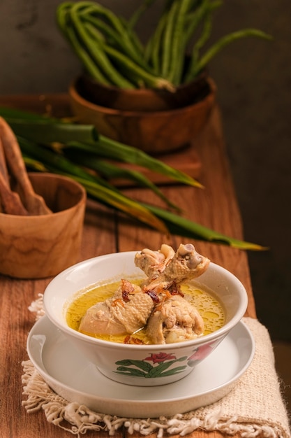 Opor Ayam is served on a wooden table. Opor is a traditional Indonesian food made from chicken cooked with coconut milk sauce