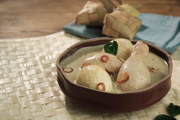 Opor ayam telur, pollo e uova sode cotte nel latte di cocco dall'indonesia, servite con lontong o ketupat e sambal. piatto popolare per lebaran o eid al-fitr