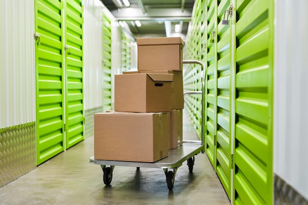 Foto oppervlakte beeld van kar met kartonnen dozen in lege hal van self storage facility, kopieer ruimte