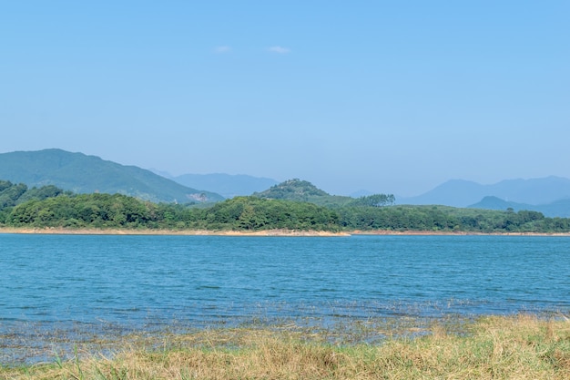 Opposite the lake is a mountain and the shore is a grassland