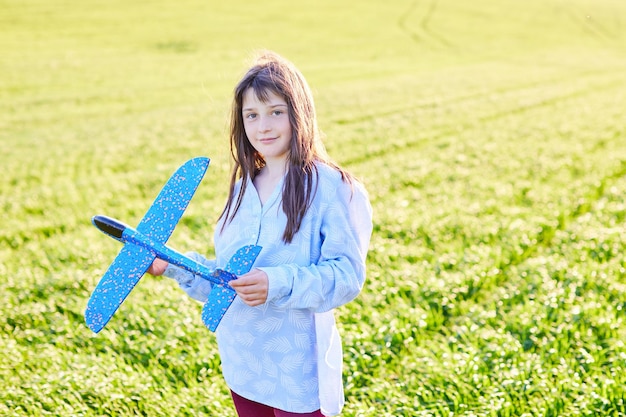 Oprechte emoties Gelukkig klein meisje dat op het veld rent met een blauw speelgoedvliegtuig in hun handen