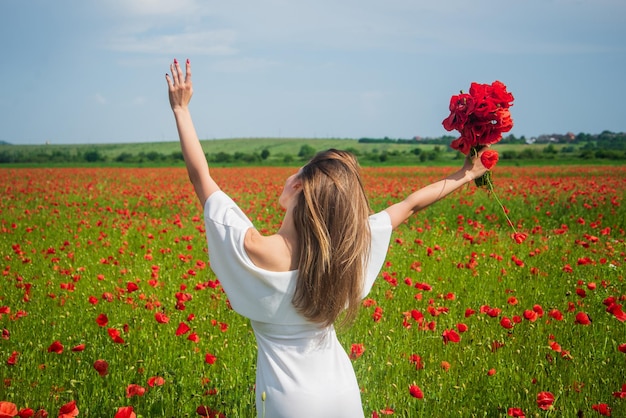 Oprechte emoties zomer of lente natuur seizoensgebonden schoonheid landschap jong meisje in witte jurk wandeling in weide vakantie gevoel van vrijheid mooie vrouw verzamelen rode papaver bloemboeket in veld