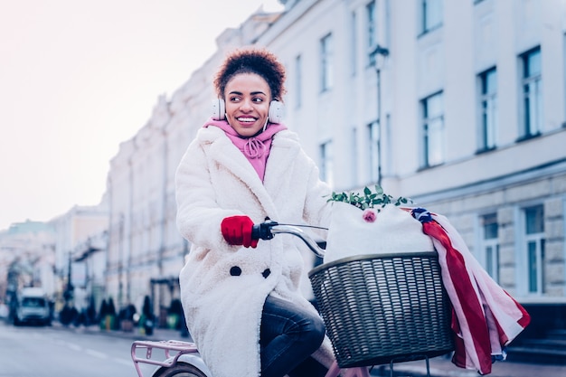 Oprechte glimlach. Opgetogen internationale vrouw die positiviteit uitdrukt tijdens het fietsen