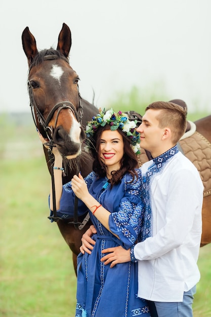 Oprechte glimlach van een vrouw in feestelijke kleding die naast de man staat en het paard achter het hoofdstel vasthoudt