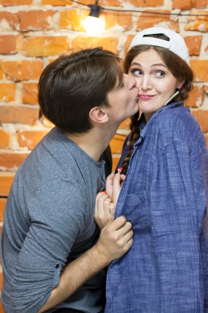 Oprechte man kust een meisje tegen een bakstenen muur