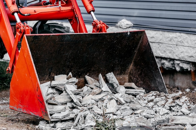 Foto opruimen van bouwafval de bak van de tractor is gevuld met betonafval en straatstenen