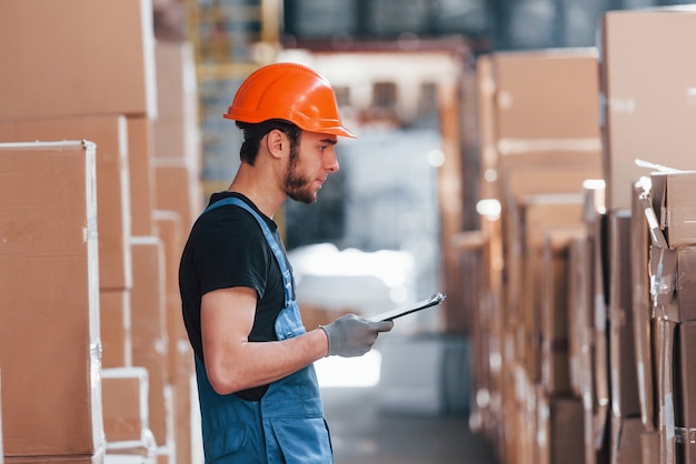 Opslagmedewerker in uniform en notitieblok in handen controleert de productie.